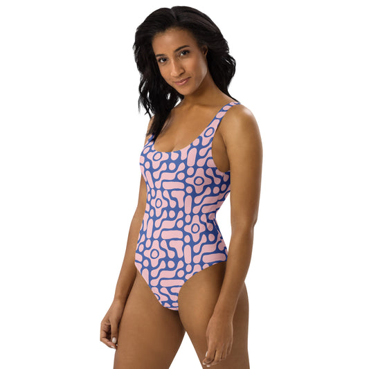 Woman wearing a pink and blue patterned one-piece swimsuit on a white background
