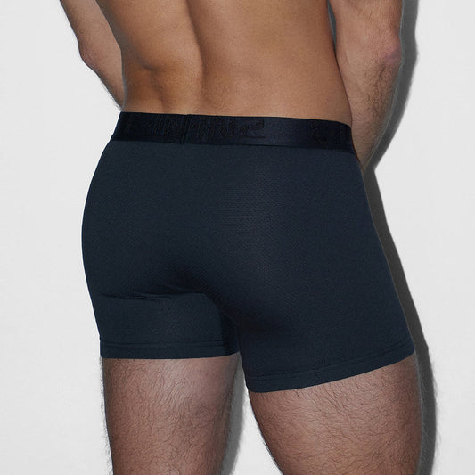 Rear view of a man wearing dark navy blue boxer briefs against a light gray background.