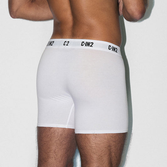 Person wearing white boxer briefs with a brand logo on the waistband against a light background