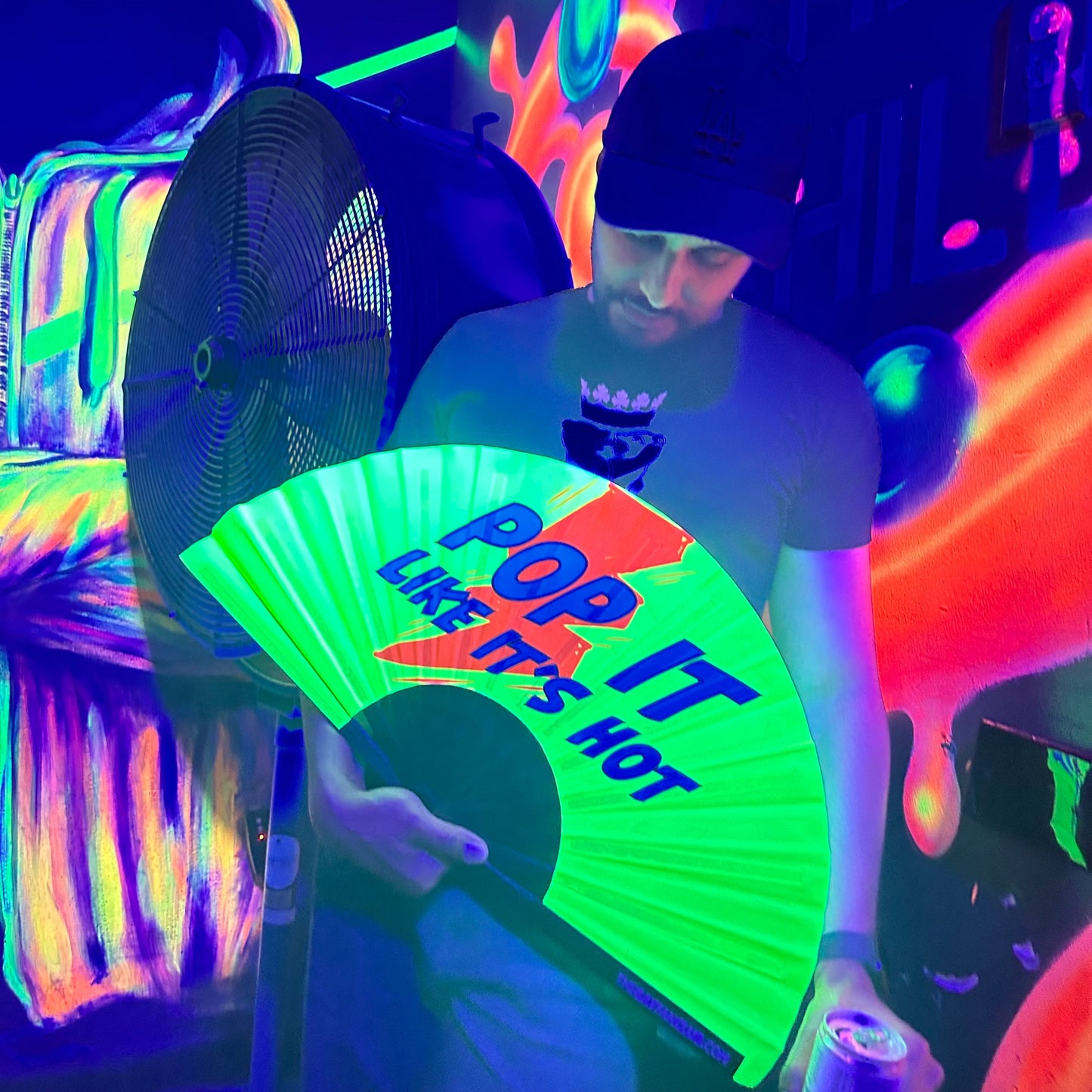 Person holding a glowing green clack fan with text in a neon-lit setting