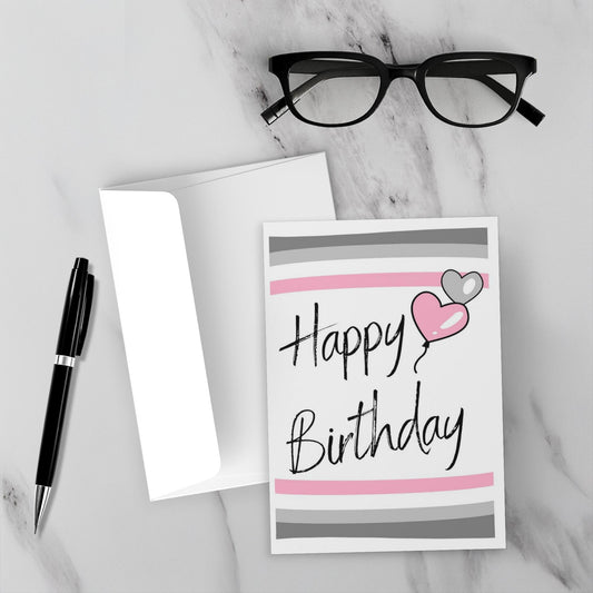 demigirl Birthday card with hearts and 'Happy Birthday' text shown on a marble surface with glasses and pen.