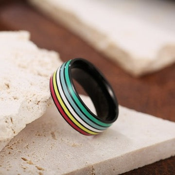 Ring with multicolored disability pride stripes on a stone surface