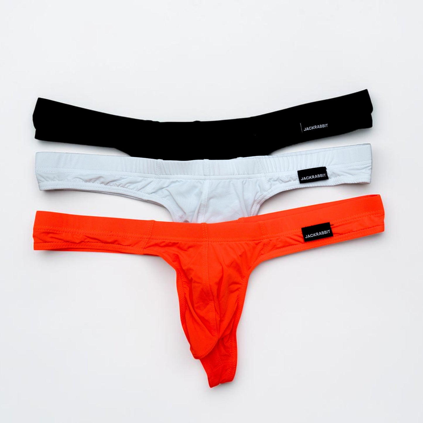 Three pairs of men's underwear in black, white, and orange on a light gray background.