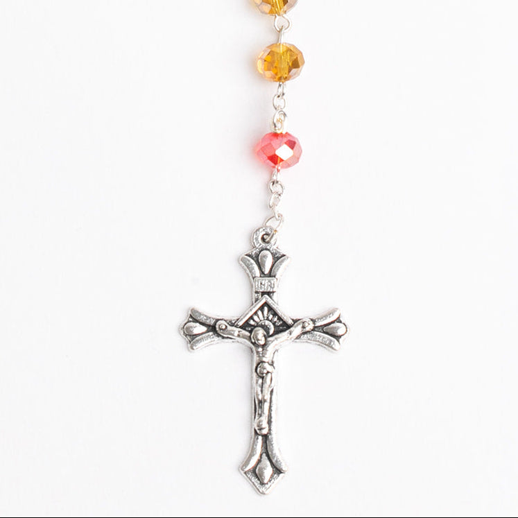 close up detail of Multicolored beaded rosary with a silver cross on a white background