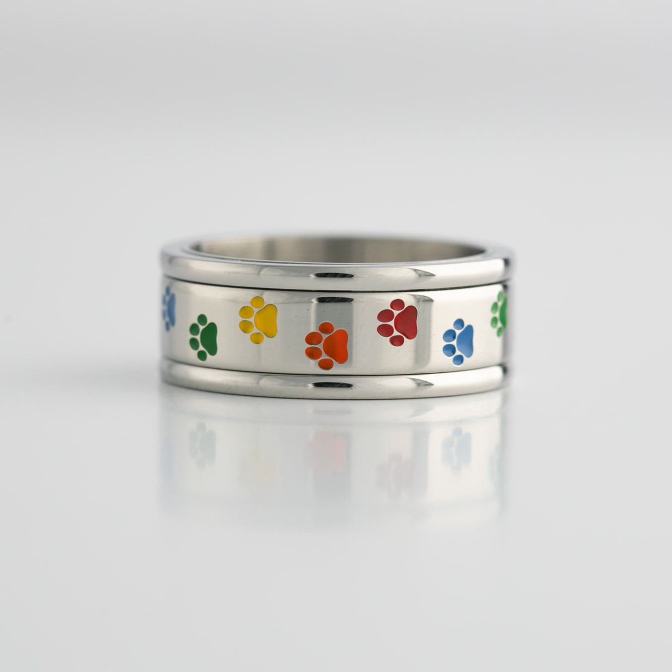 Silver ring with lgbtq rainbow colored paw prints on a light gray background