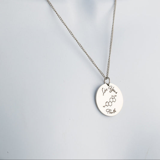 Silver necklace with a round pendant that says 'live your truth' with a chemical symbol on a light gray background