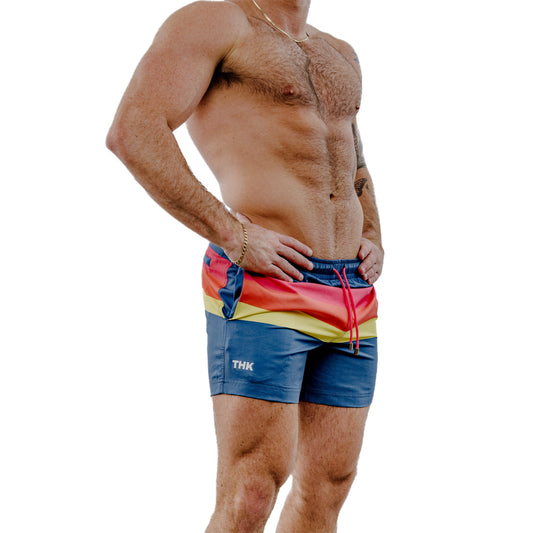 Man wearing colorful swim shorts with a white background