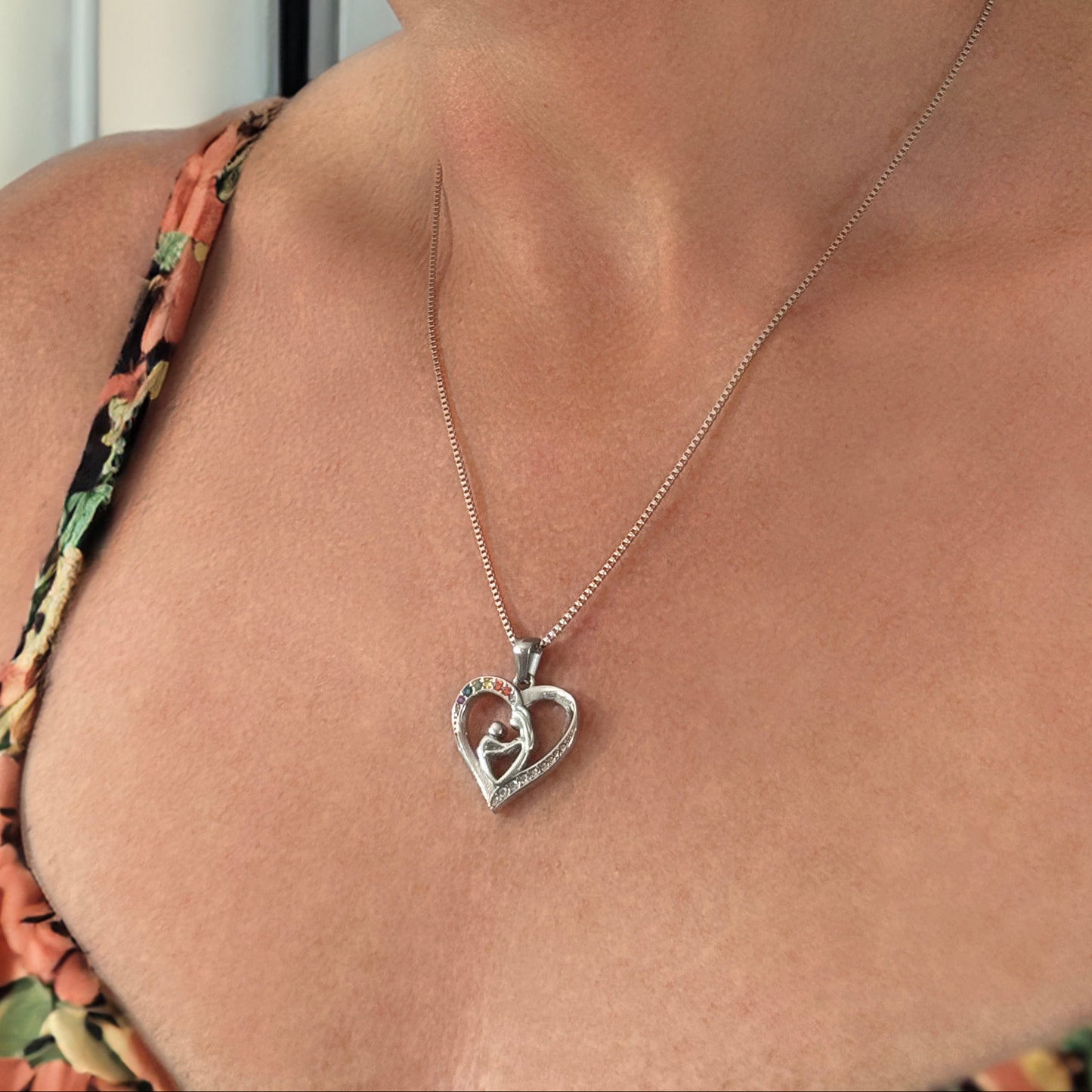 Woman wearing a floral top and a silver heart-shaped necklace.