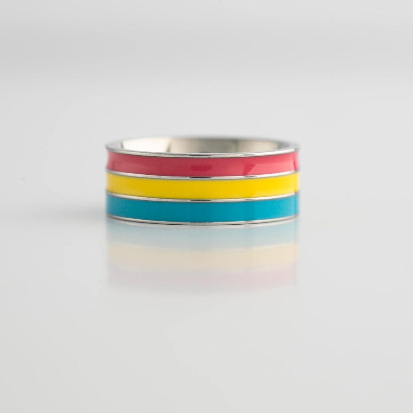 Ring with pansexual pride colored stripes on a light gray background