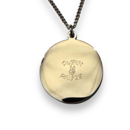 Gold pendant with ' Quier Peace' engraving on a chain against a white background