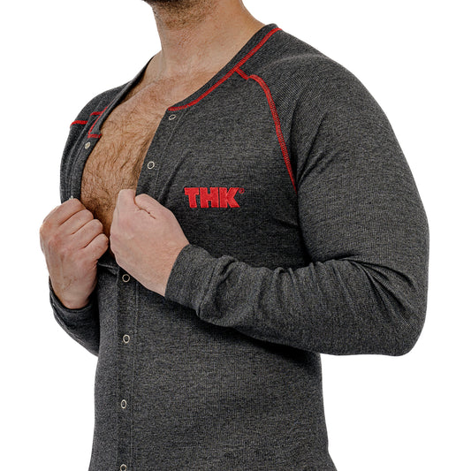Man wearing a gray union suit with red accents and 'THK' logo, lifting shirt to reveal chest.