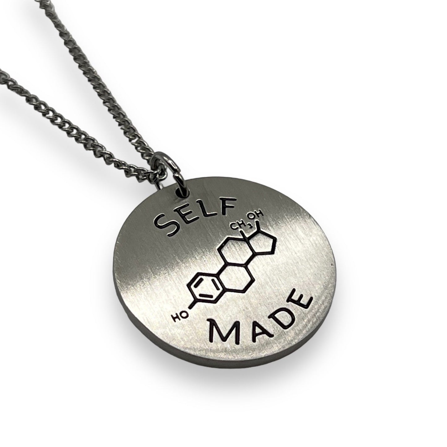 Silver necklace with a round pendant featuring the text 'SELF MADE' and a chemical structure diagram.