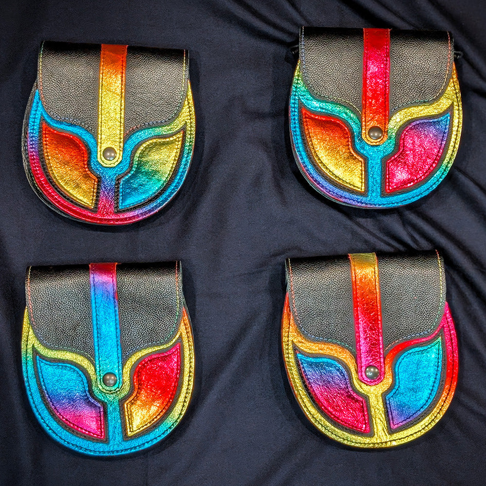 Four black leather sporrans with vibrant rainbow-colored appliques, arranged in a 2x2 grid on a dark navy fabric background.