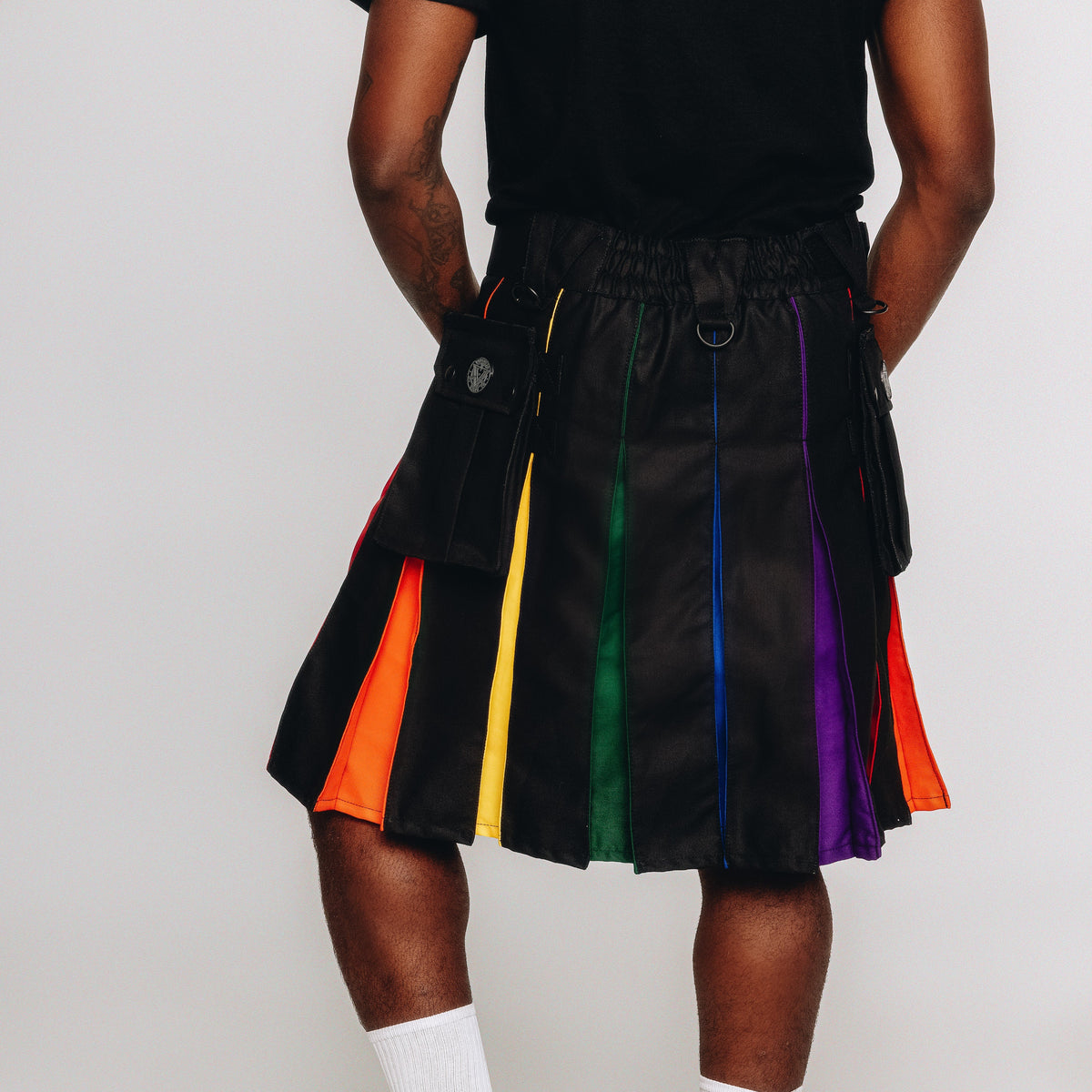 Person wearing a black kilt with rainbow stripes on a white background
