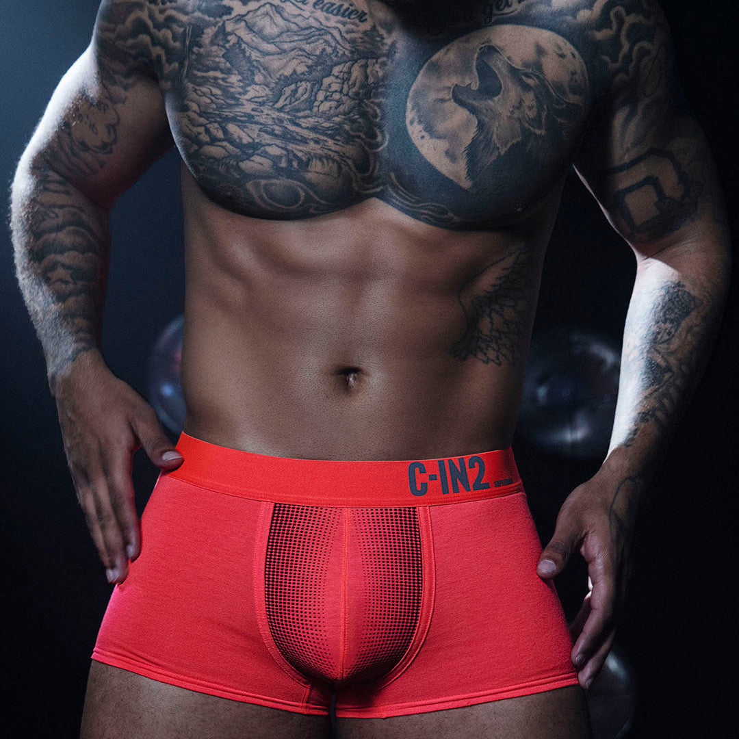 Man wearing red underwear with 'C-IN2' branding against a dark background