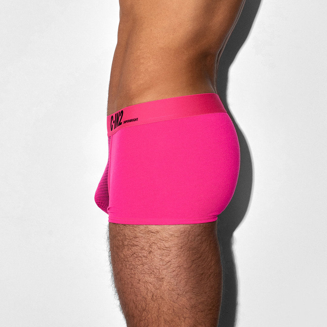 A close-up side view of a model wearing bright pink underwear, showing the waistband with a small black logo and the side mesh detail.