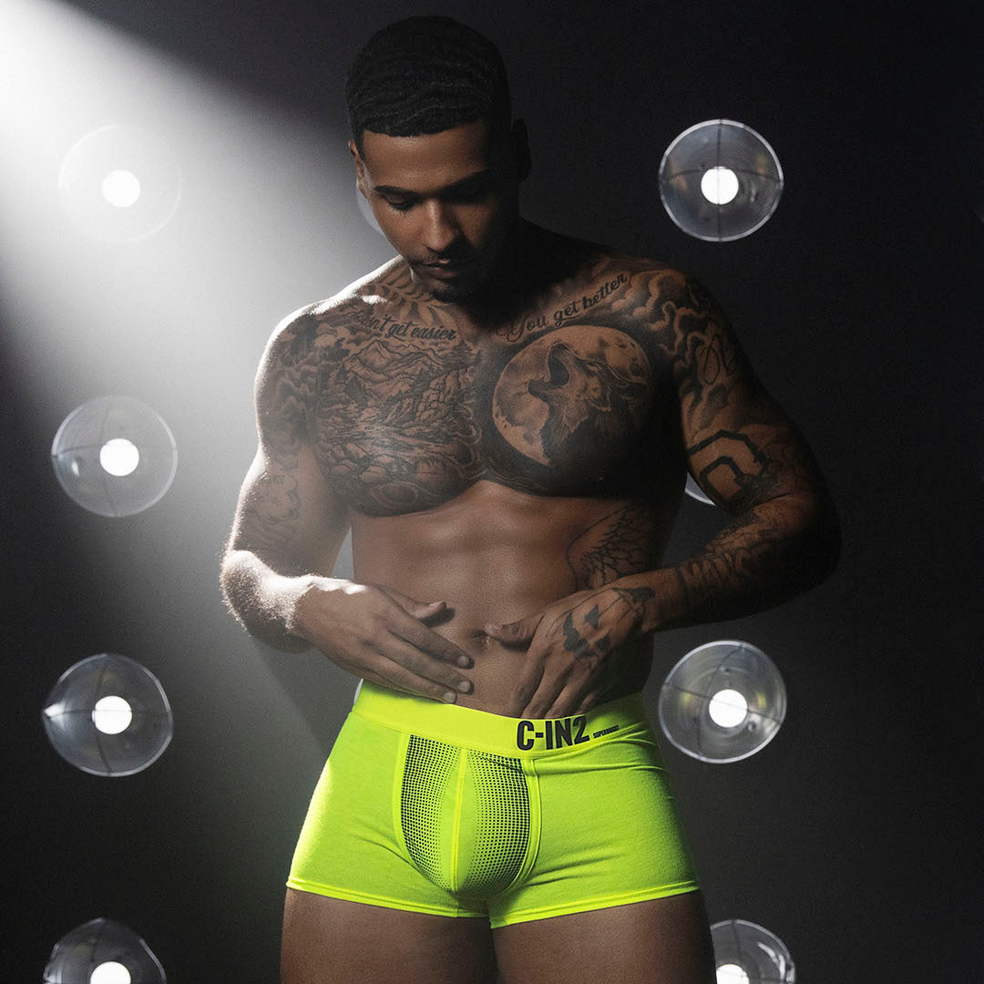 Man wearing bright green underwear with a dark background and spotlight effect