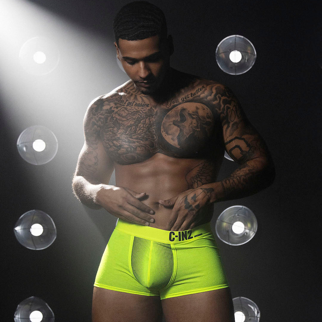 Man wearing bright green underwear with a dark background and spotlight effect