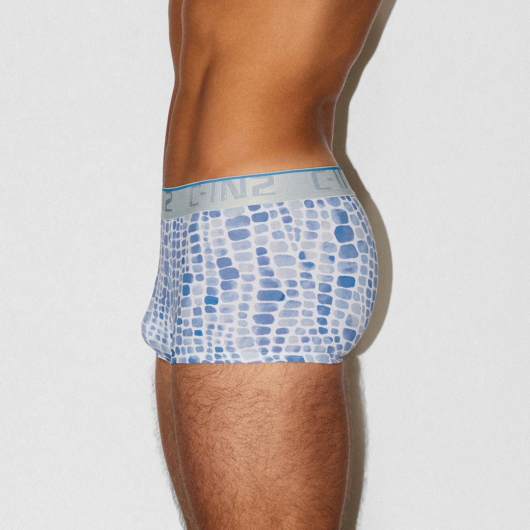 A side profile view of a man wearing C-IN2 boxer briefs with a blue and white geometric pattern, set against a plain light gray background.