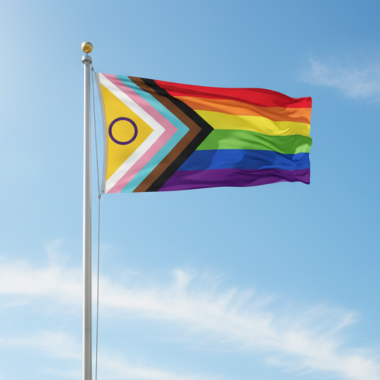 A intersex inclusive Progress Pride flag waves on a tall silver flagpole outdoors against a bright blue sky with light clouds. 
