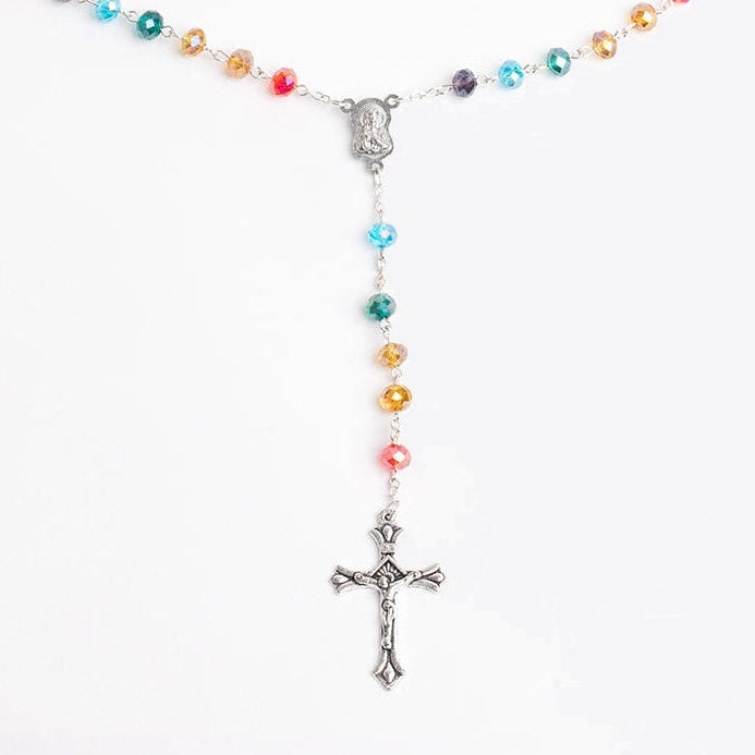 Colorful rainbow beaded rosary with a cross on a white background