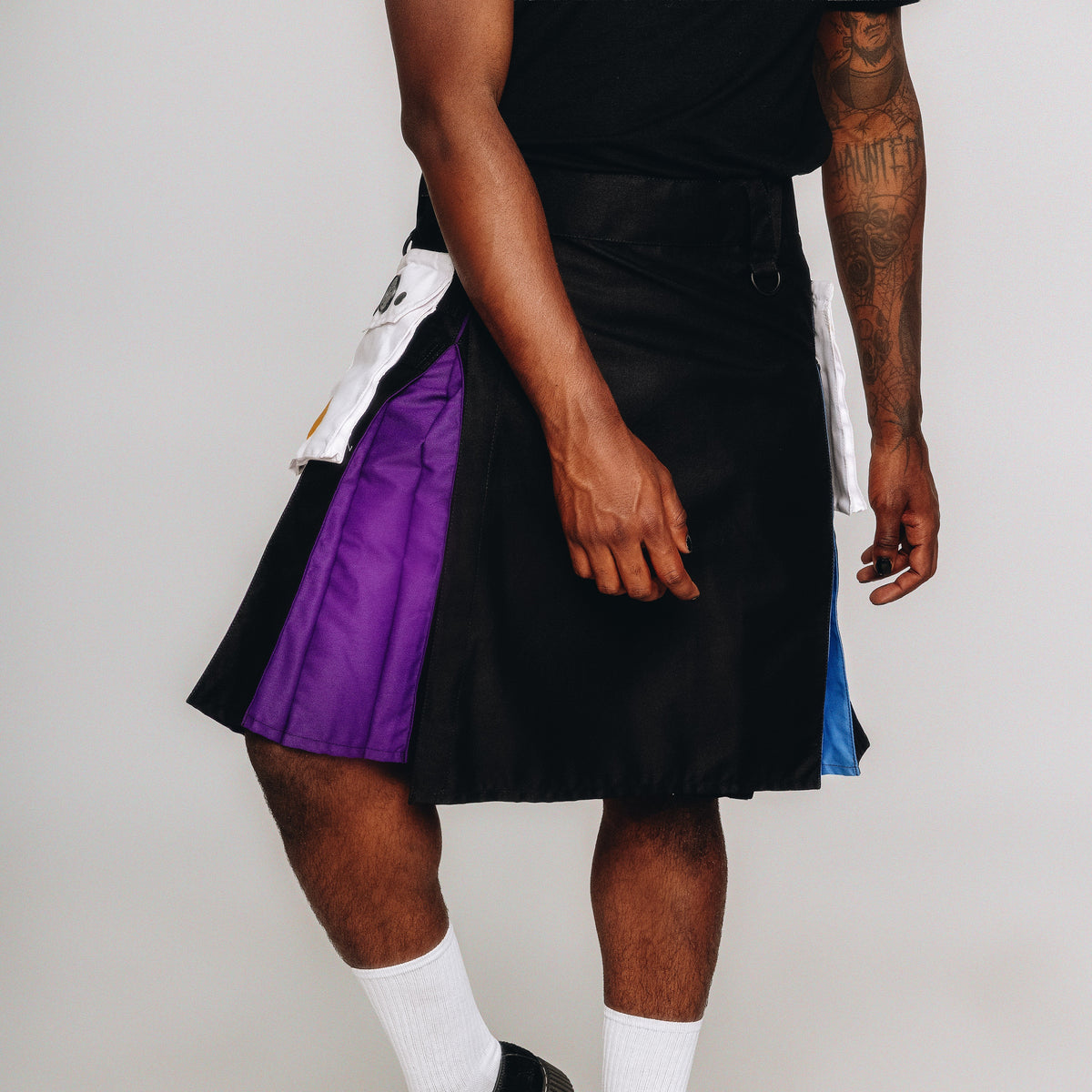 Person wearing a black and purple kilt on a white background