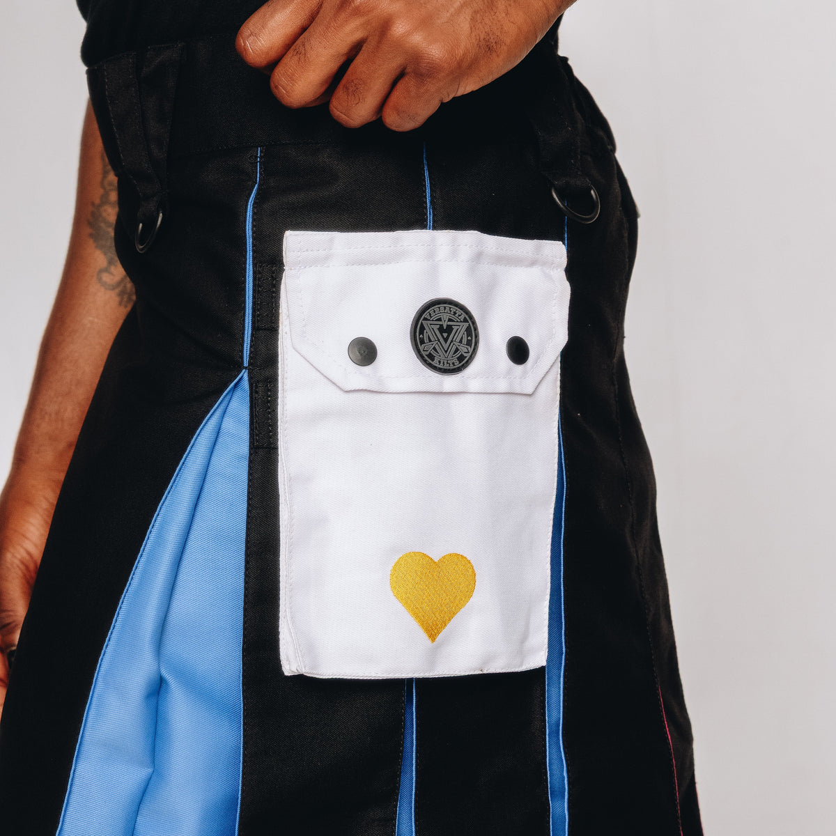 Person wearing a black and blue kilt with a white pocket featuring a yellow heart design.