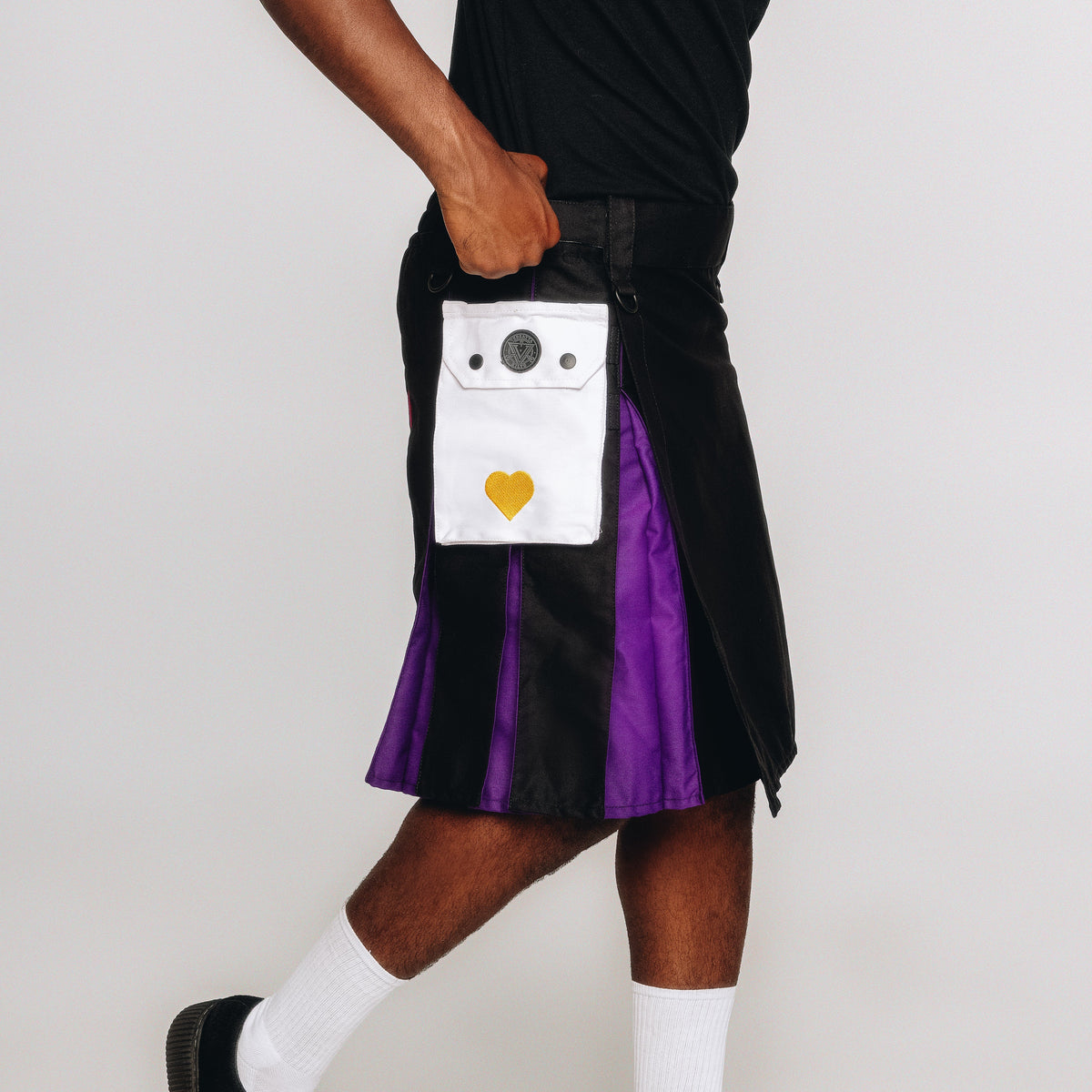 Person wearing a black and purple kilt with a unique pocket design on a white background