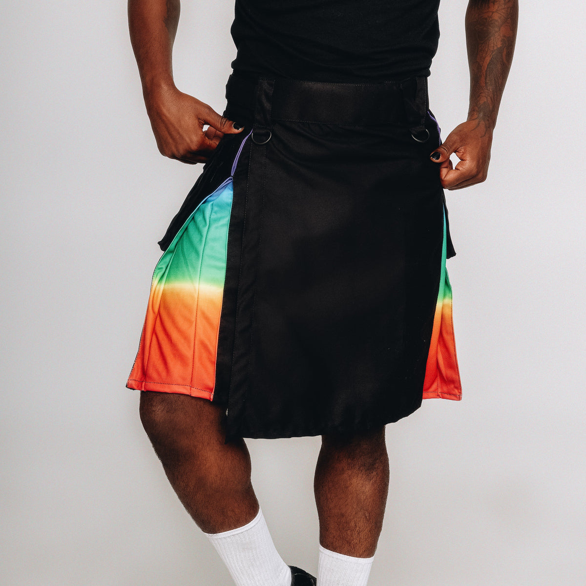 Person wearing a black kilt with rainbow sides on a white background
