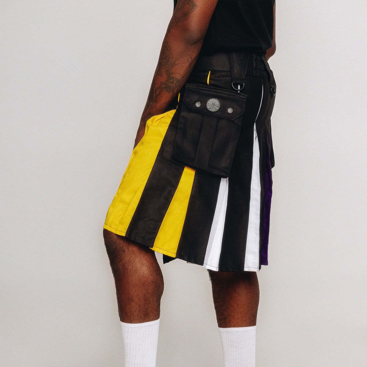 Person wearing a black, yellow, and white striped kilt with a white background