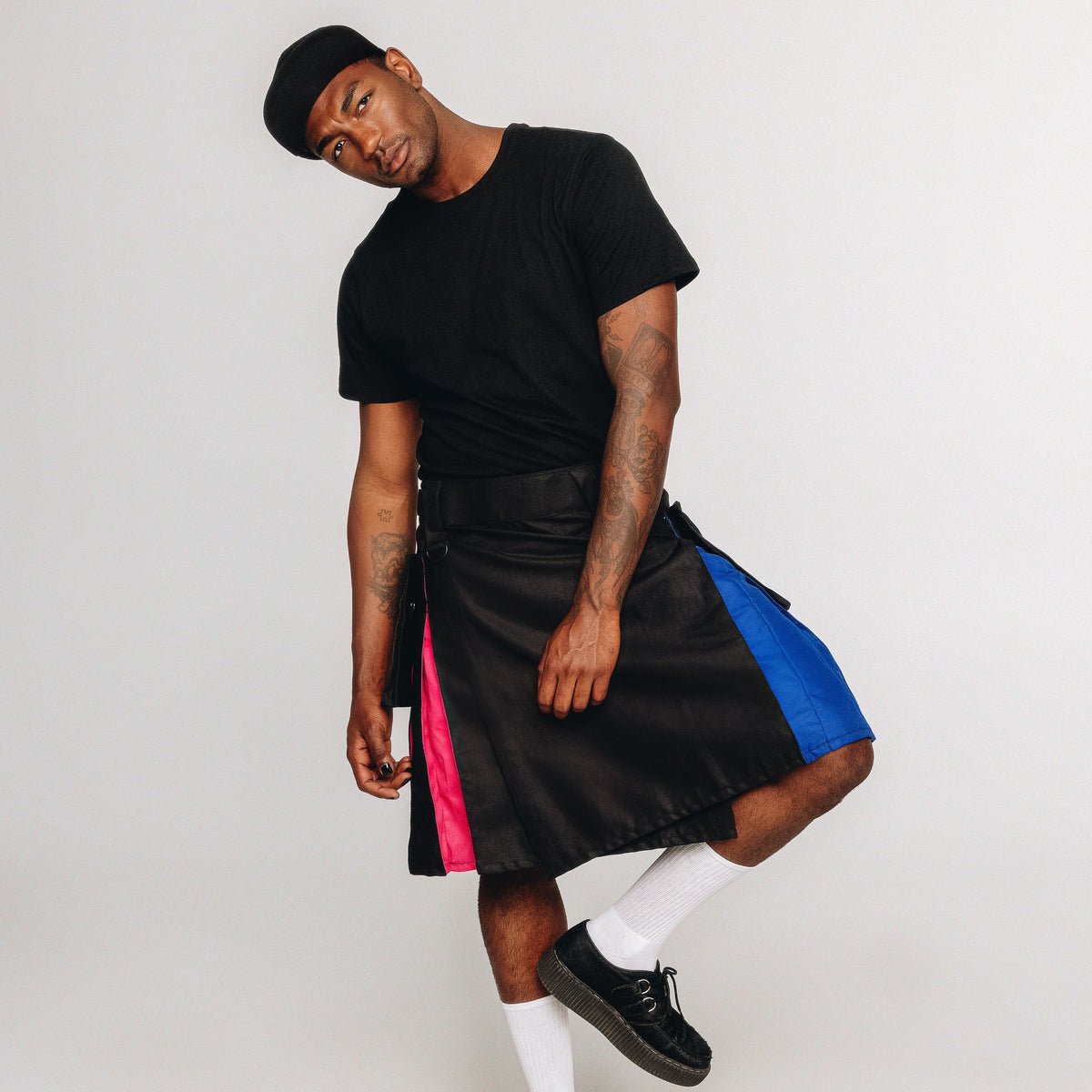 Person wearing a black kilt with rainbow accents on a white background