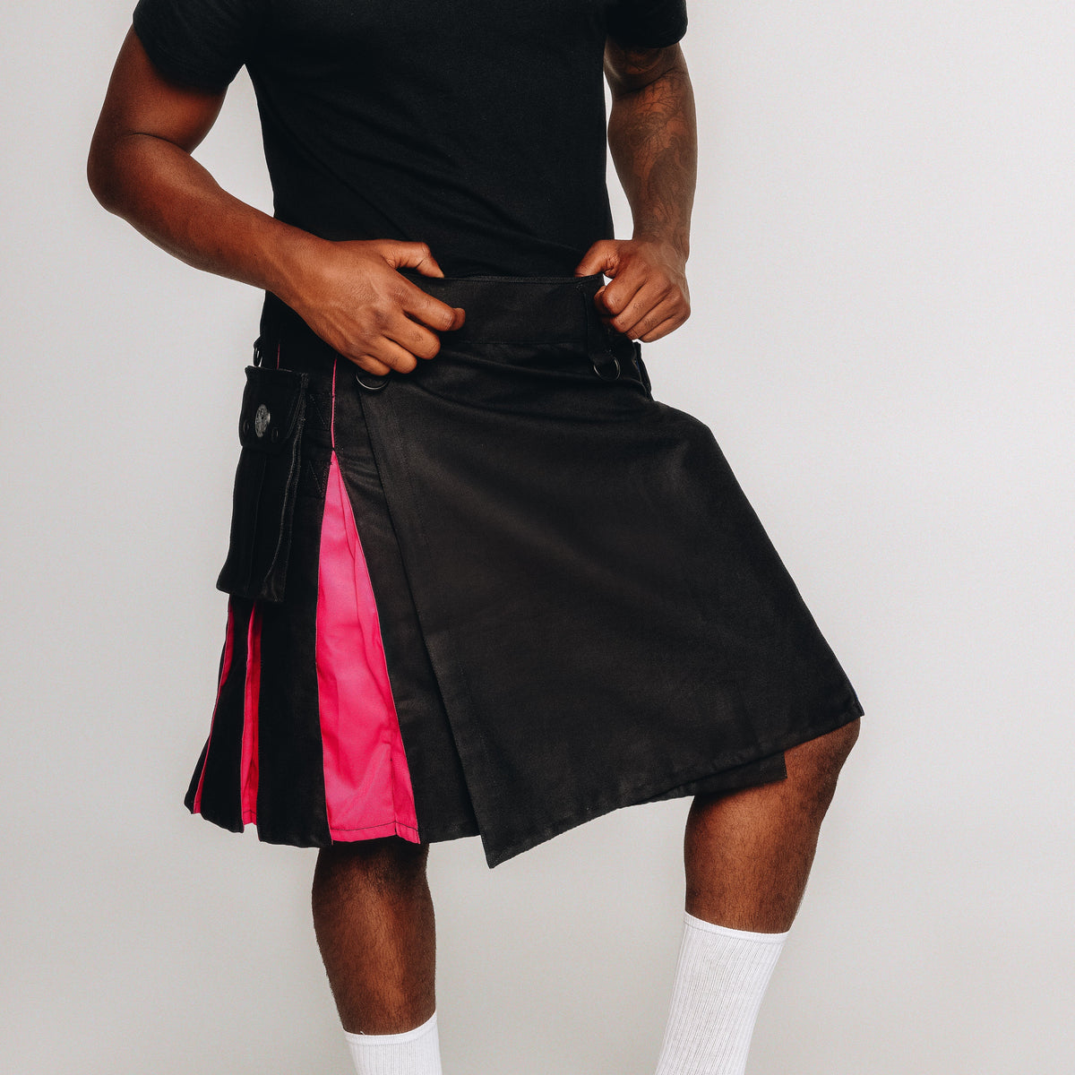 Person wearing a black and pink kilt on a plain background