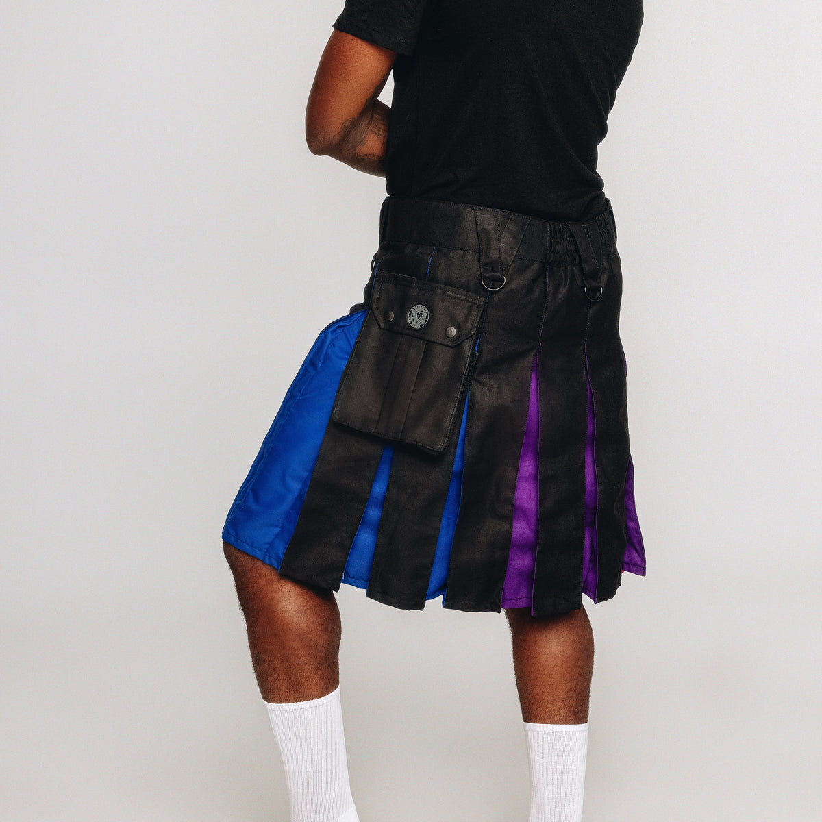 Person wearing a black kilt with blue and purple accents on a white background