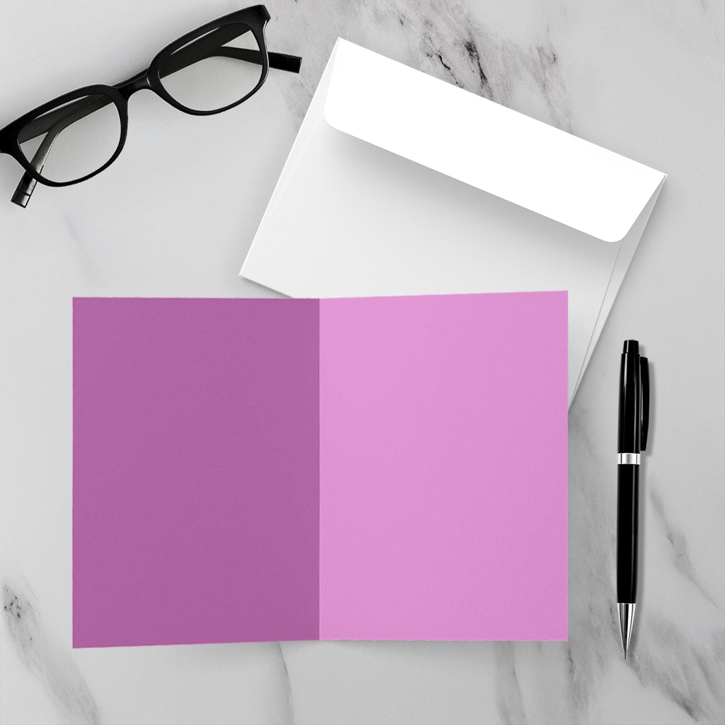 Light purple, inside blank card, white envelope, black pen, and glasses on a marble surface
