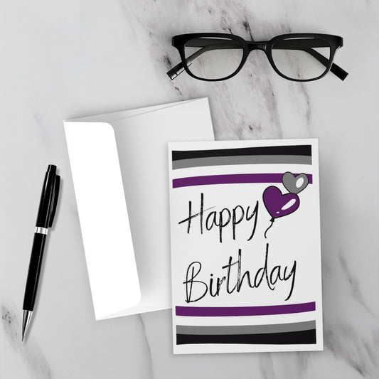 Birthday card with purple heart and 'Happy Birthday' text on a marble surface with glasses and pen.
