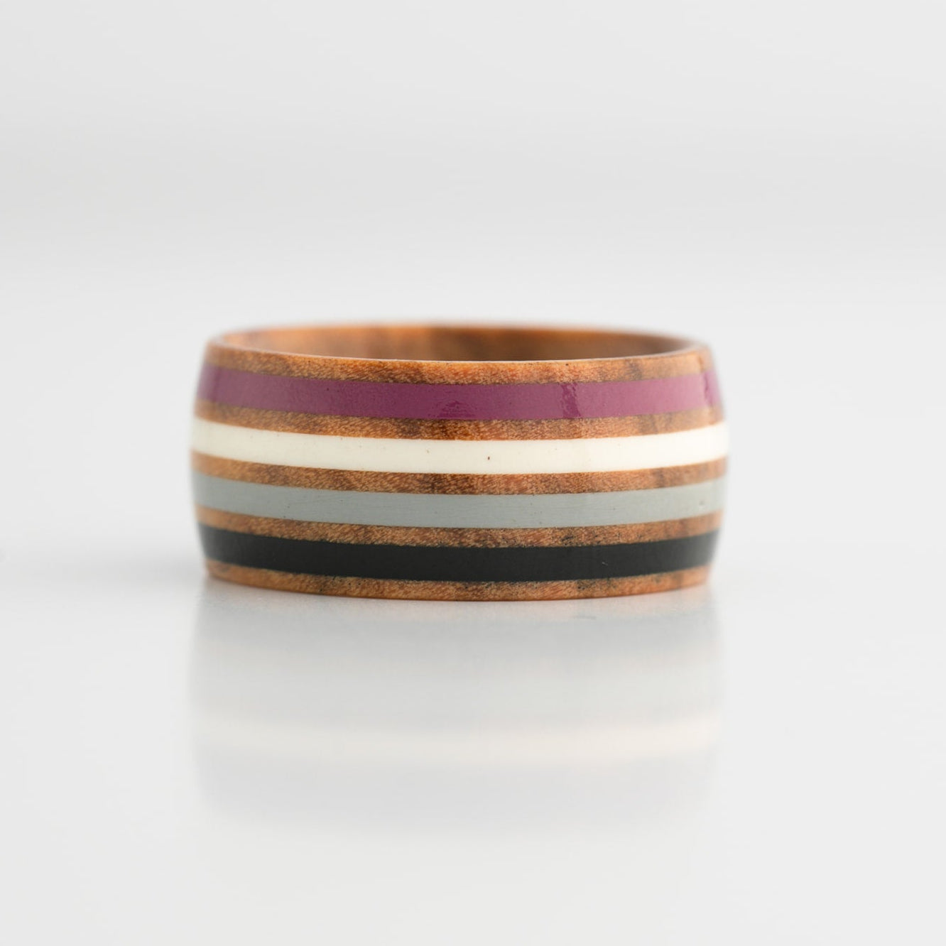 Wooden ring with asexual pride striped design on a white background