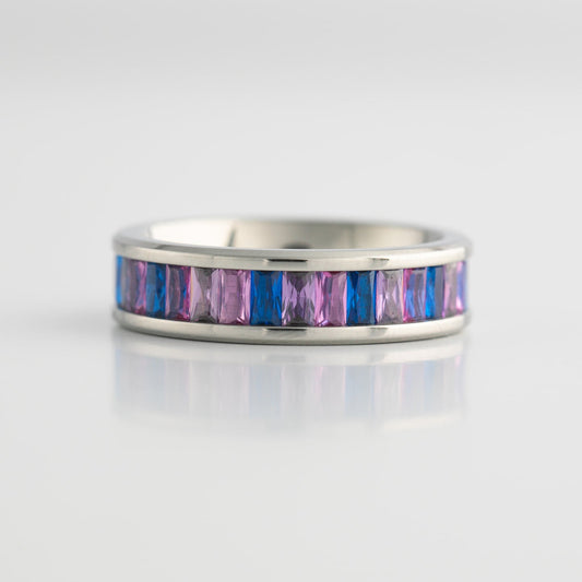 Silver ring with bisexual pride colored gemstones on a light gray background