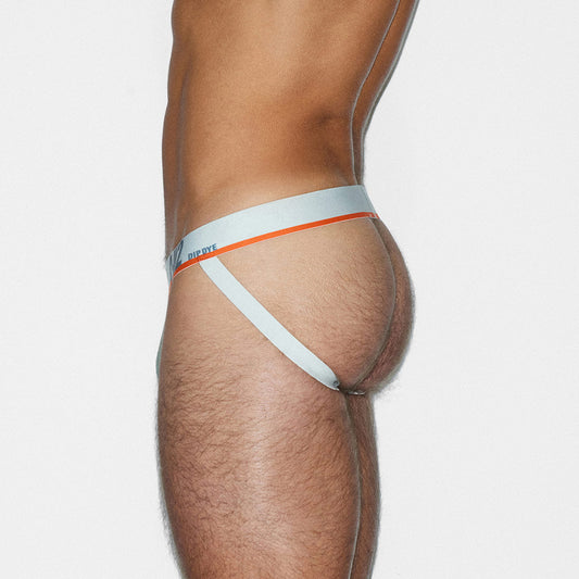 A close-up side view of a male model wearing a white jock-style brief with a thin orange stripe and a small blue C-IN2 brand logo on the waistband, against a light gray studio background.