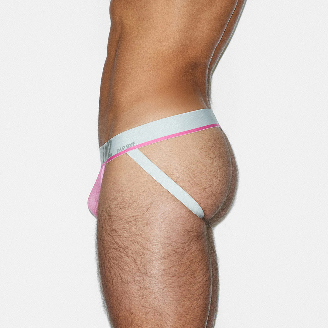 Side view of a man wearing a jock-style underwear in light gray with a bright pink side panel and trim, against a plain light gray background.