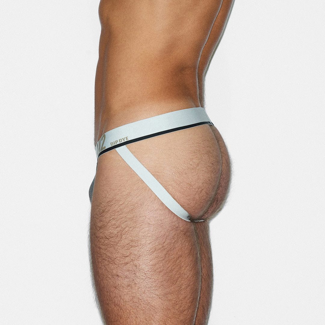 Partial view of a person wearing a light gray thong on a white background