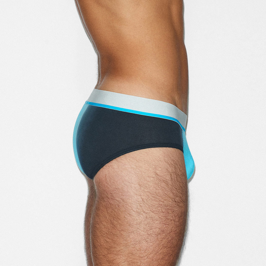 Side view of a man wearing low-rise briefs with a black body, light blue side panels, and a white waistband.