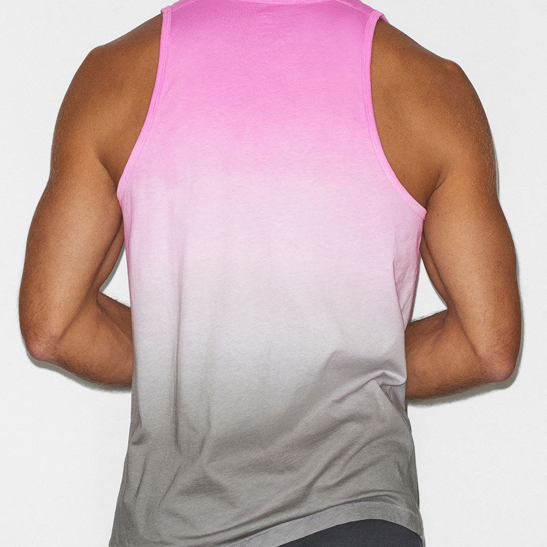 Person wearing a pink to gray gradient tank top on a plain background