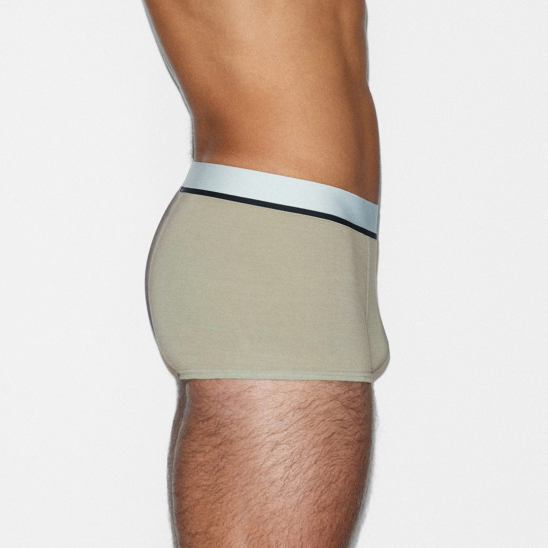 Beige underwear with a white waistband on a plain background