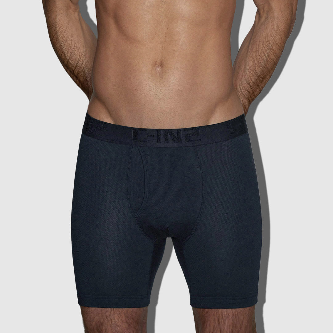 A man's lower torso wearing dark navy blue boxer briefs with a C-IN2 tonal logo on the waistband, shown against a light gray background.