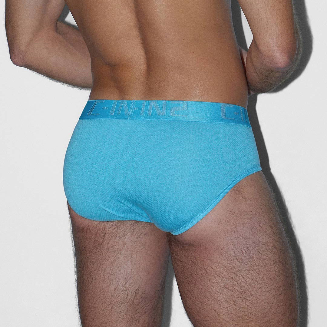 Person wearing a blue underwear on a plain background