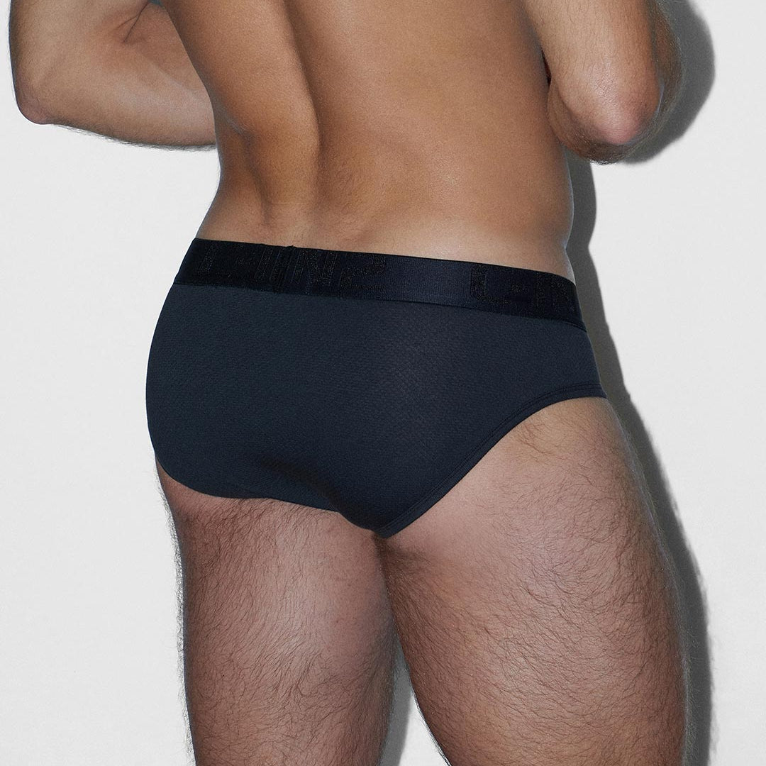 Rear view of a man wearing black briefs against a light gray background.