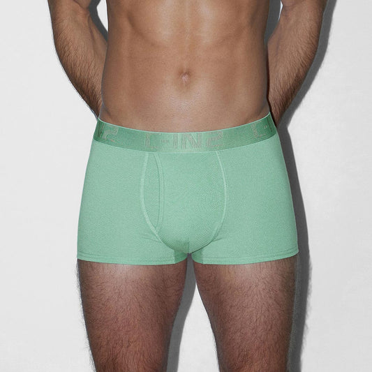 A man wearing sage green boxer briefs, shown from the back against a plain light gray background.