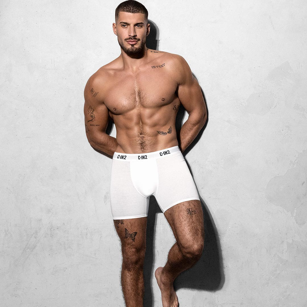 Man wearing white boxer briefs against a gray background