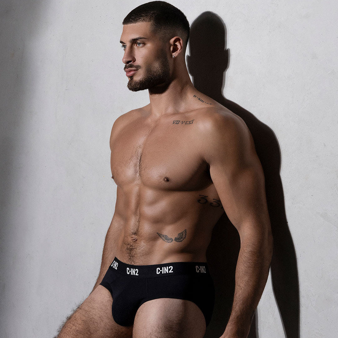 Man wearing black underwear with visible branding against a neutral background