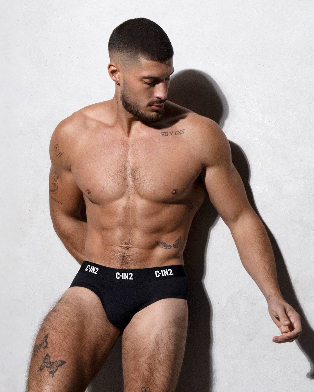 Man wearing black underwear with visible C-IN2 branding against a white background